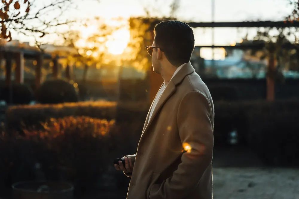 A man in a camel overcoat at golden hour